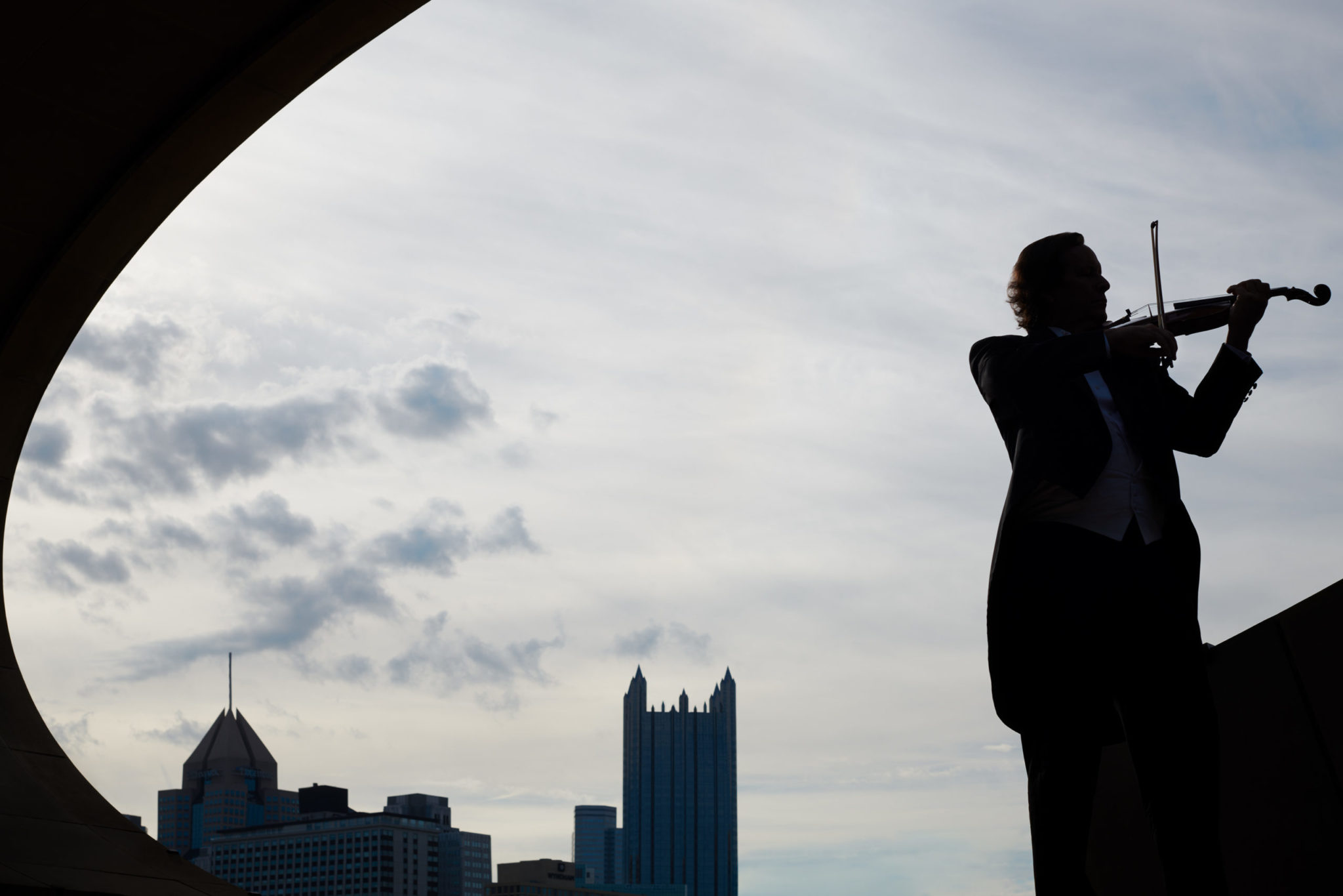 backlit violinist playing outdoors in downtown pittsburgh