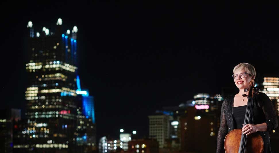 Violinist from Pittsburgh Symphony Orchestra Standing in front of Pittsburgh Cityscape at Night